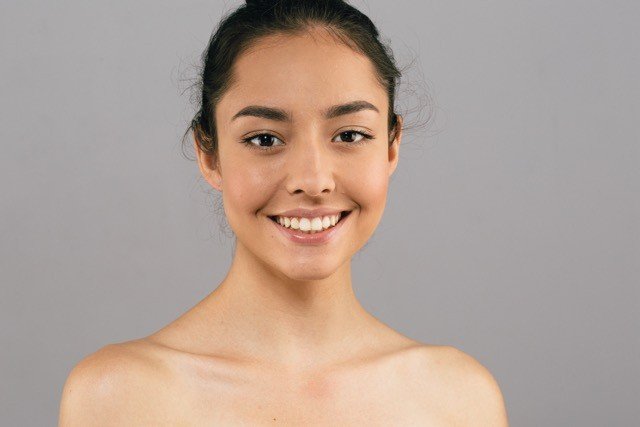 The image is of a person smiling for the camera and show her natural beauty and glowing skin.