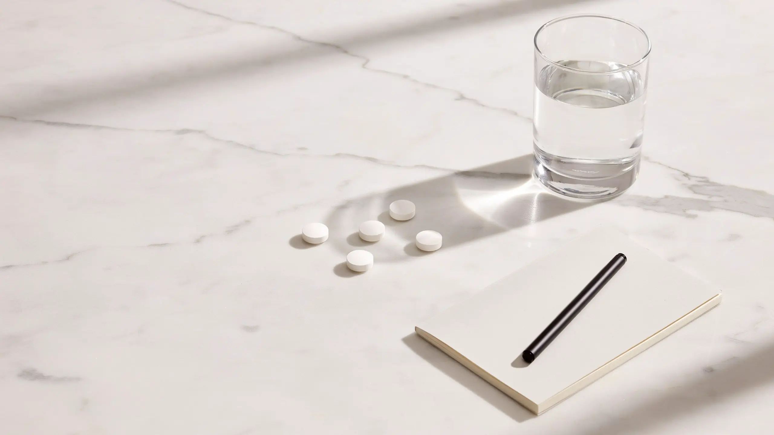 Clean flat-lay of erectile dysfunction medication tablets beside a glass of water representing the range of PDE5 inhibitor treatment options available in the UK