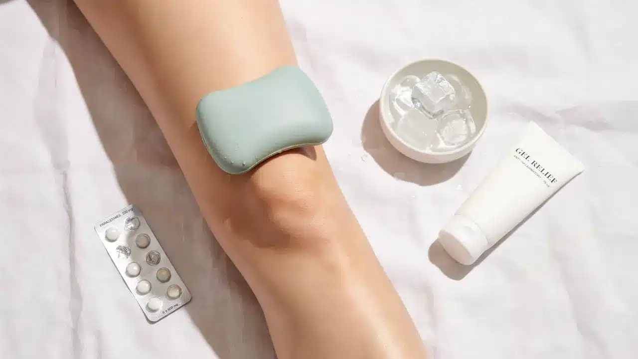 Woman resting knee with ice pack and paracetamol showing the fastest way to relieve knee pain at home recommended by Dr SNA Clinic London