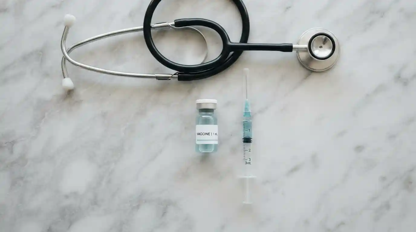 Stethoscope, vial, and syringe on marble surface representing P-Shot and penile filler treatment